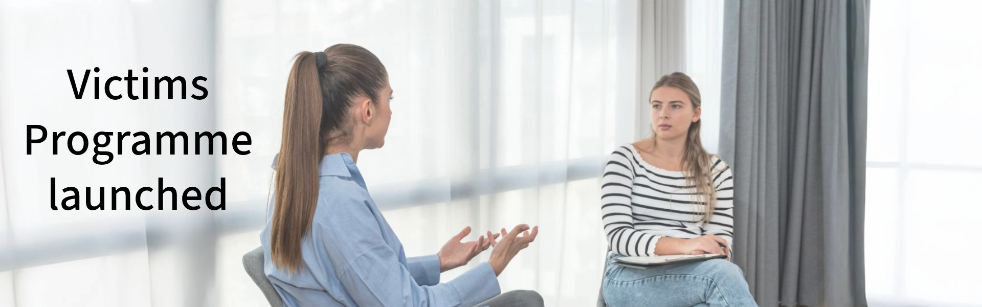 Photo of two casually dressed women in a meeting. Text reads: Victims Programme launched